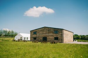 image shows wooden cladded winery building with white marquee to the side